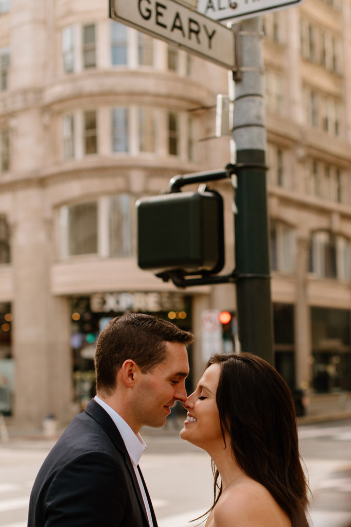 Sydney Jai Photography - San Francisco city elopement, bride and groom touching nosing and smiling at each other, bride wearing satin off the shoulder wedding dress, groom wearing a classic black suit
