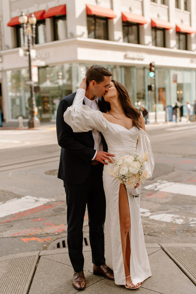 Sydney Jai Photography - San Francisco city elopement, bride and groom kissing, bride wearing satin off the shoulder wedding dress, groom wearing a classic black suit