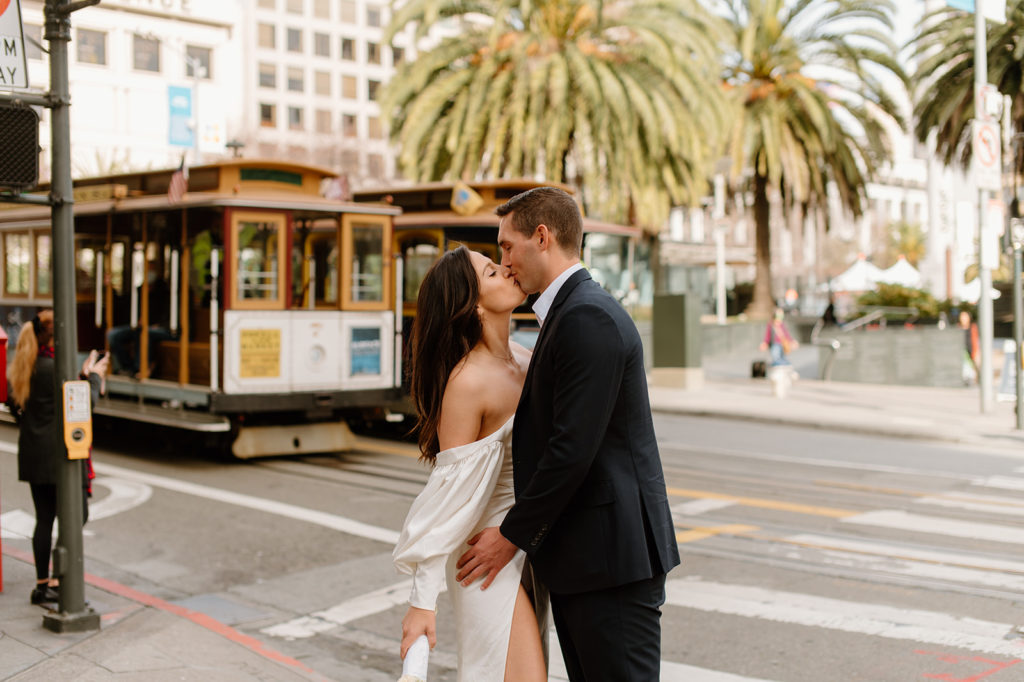 Sydney Jai Photography - San Francisco city elopement, bride and groom kissing and holding each other, bride wearing satin off the shoulder wedding dress, groom wearing a classic black suit