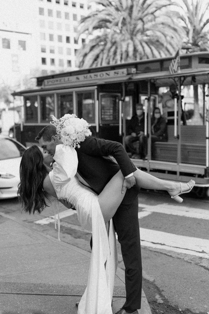 Sydney Jai Photography - San Francisco city elopement, bride and groom kissing and holding each other, bride wearing satin off the shoulder wedding dress, groom wearing a classic black suit
