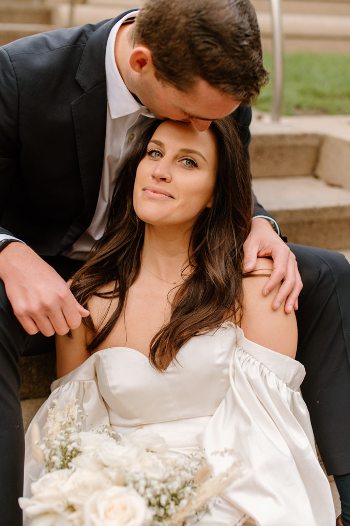 Sydney Jai Photography - San Francisco city elopement, groom kissing brides forehead, bride wearing satin off the shoulder wedding dress, groom wearing a classic black suit