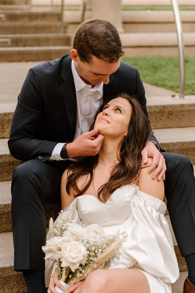 Sydney Jai Photography - San Francisco city elopement, bride and groom smiling at each other, bride wearing satin off the shoulder wedding dress, groom wearing a classic black suit